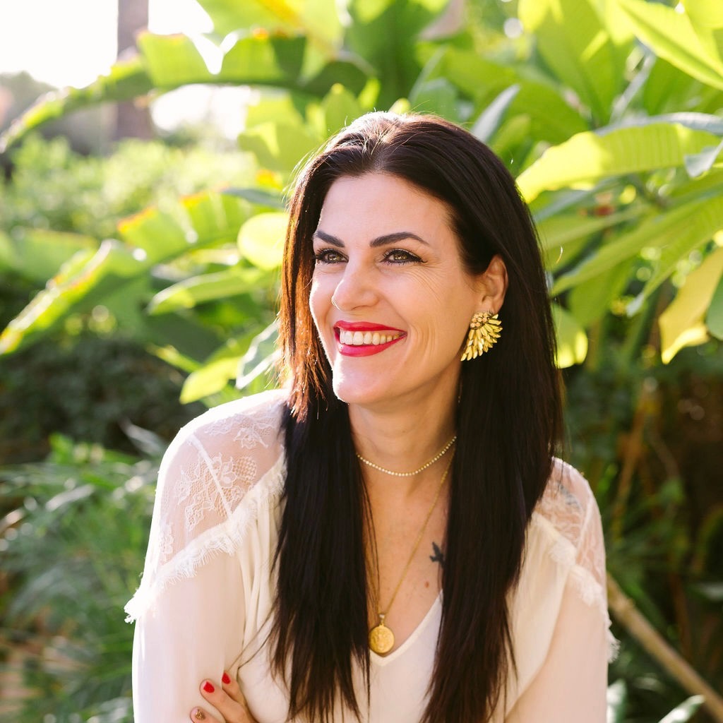 Dr. Shaleen Kendrick, smiling outdoors among green foliage